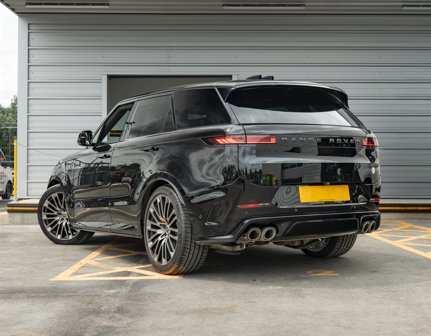 Black Range Rover parked in a designated parking space, viewed from the rear side.