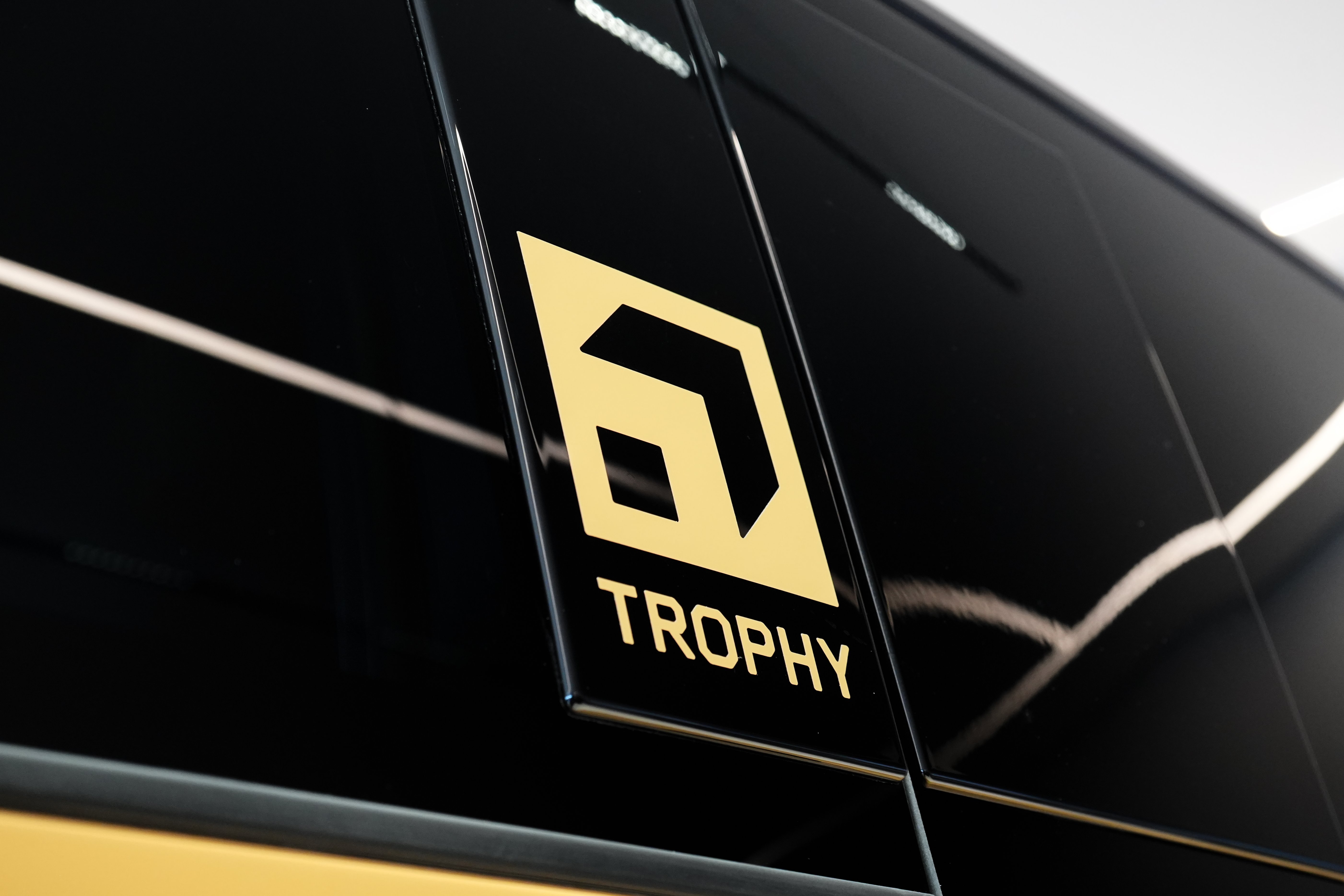 A logo with the word Trophy on a black surface of a vehicle.