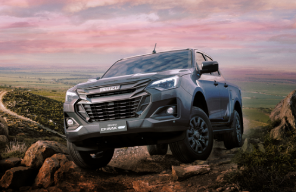 A grey Isuzu D-Max pickup truck navigates rocky terrain under a pink and purple sky.
