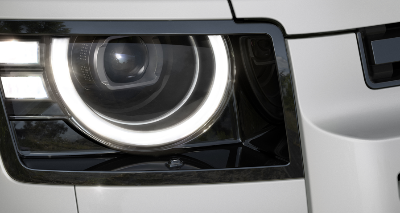 Close-up of a car's headlight with LED ring and rectangular design.