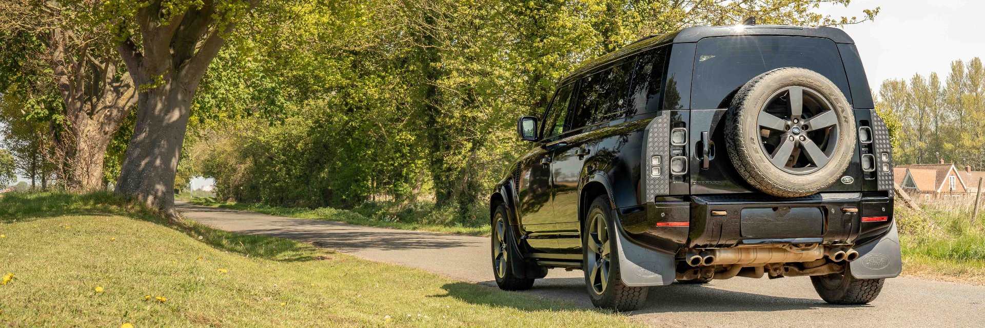 Four-wheel drive SUV on a rural road surrounded by trees.