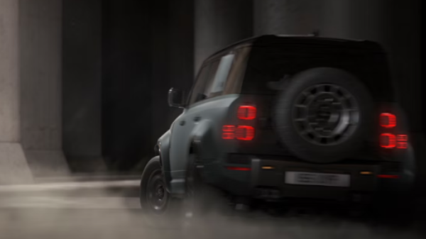 A four-wheel-drive car driving through a dusty area with bright taillights.