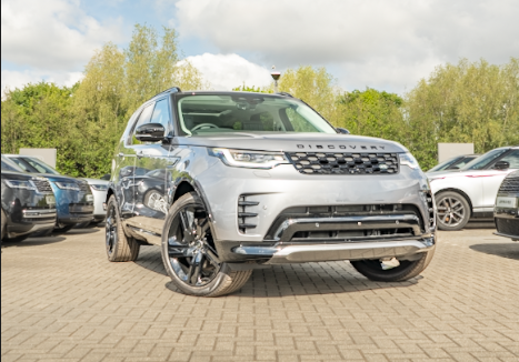 Silver SUV parked outdoors on a paved area with trees in the background.