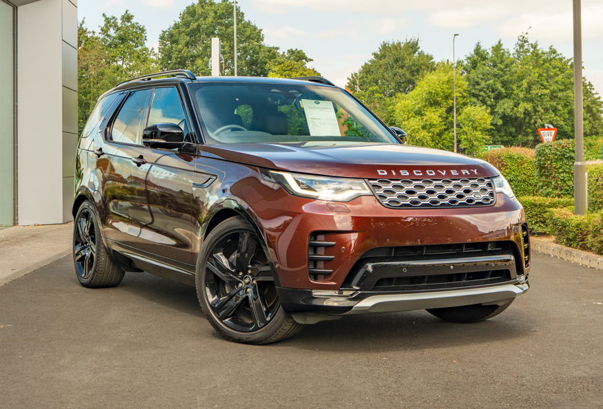 Brown SUV parked outside, facing slightly right, with Discovery on the front.