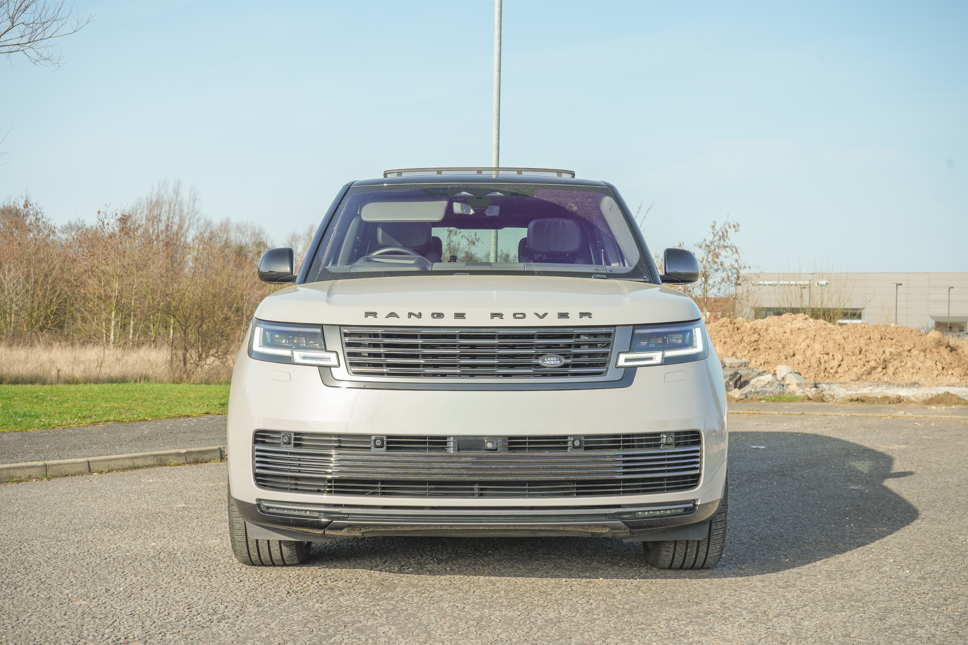 Front view of a silver Range Rover parked on pavement.