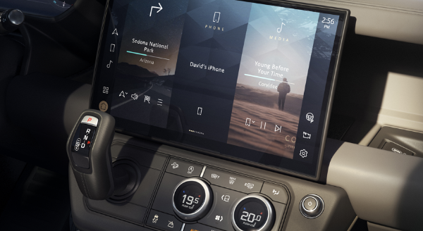 Car dashboard with touchscreen showing navigation, media, and climate controls.
