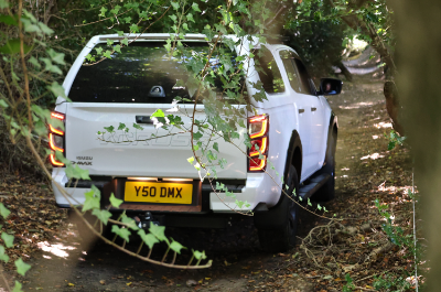 White pickup truck driving on a forest path.