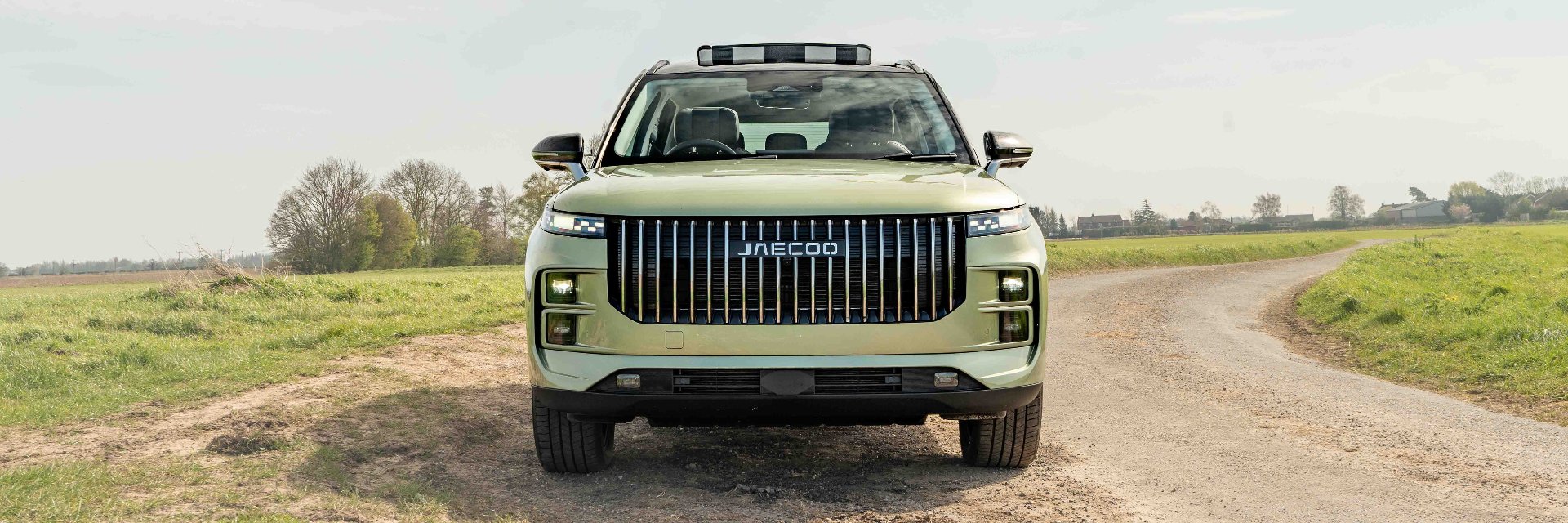 Front view of a green SUV parked on a rural dirt road.