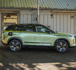 Electric SUV in side profile parked, charging at station.