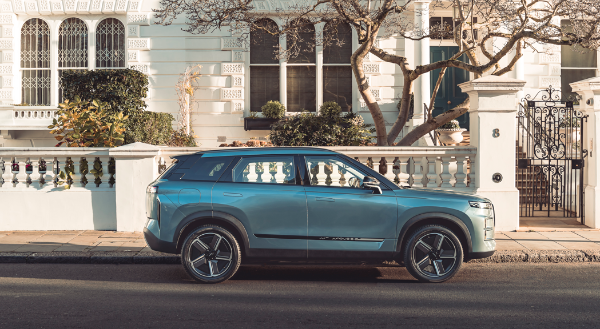 Blue SUV parked on a street outside a white townhouse.