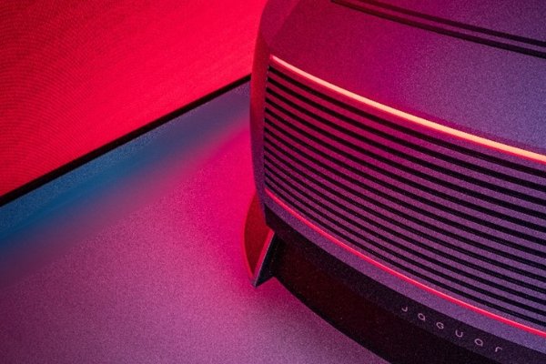 Close-up of a car front with horizontal grille and illuminated red lights.