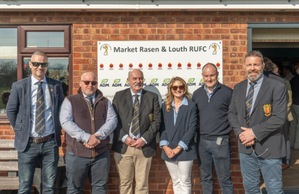 Group of six people standing outside a building with Market Rasen & Louth RUFC sign.