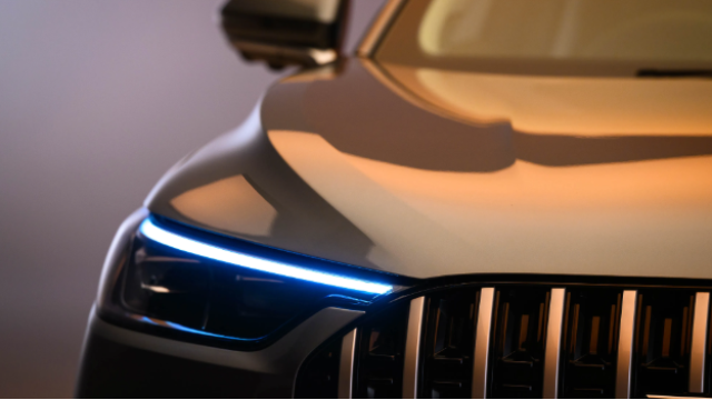 Close-up of a car's front right side, showing headlight and grille details.