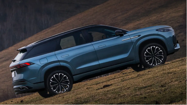 Blue SUV parked on a grassy slope, seen from the side.
