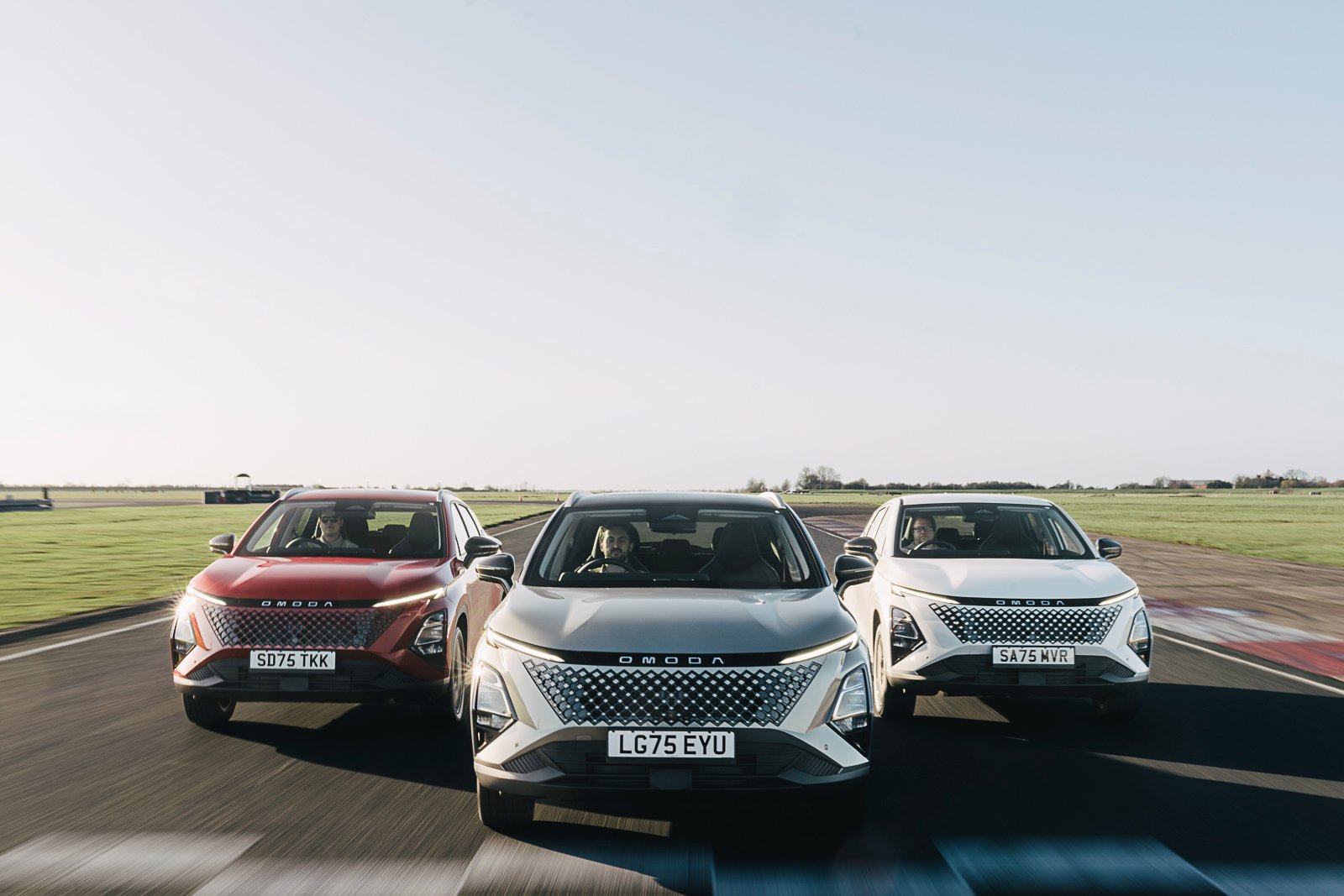 Three OMODA cars driving side by side on a track.