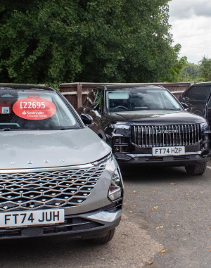 Two parked cars, the left car displays a price sticker of £22,695 on the windscreen.