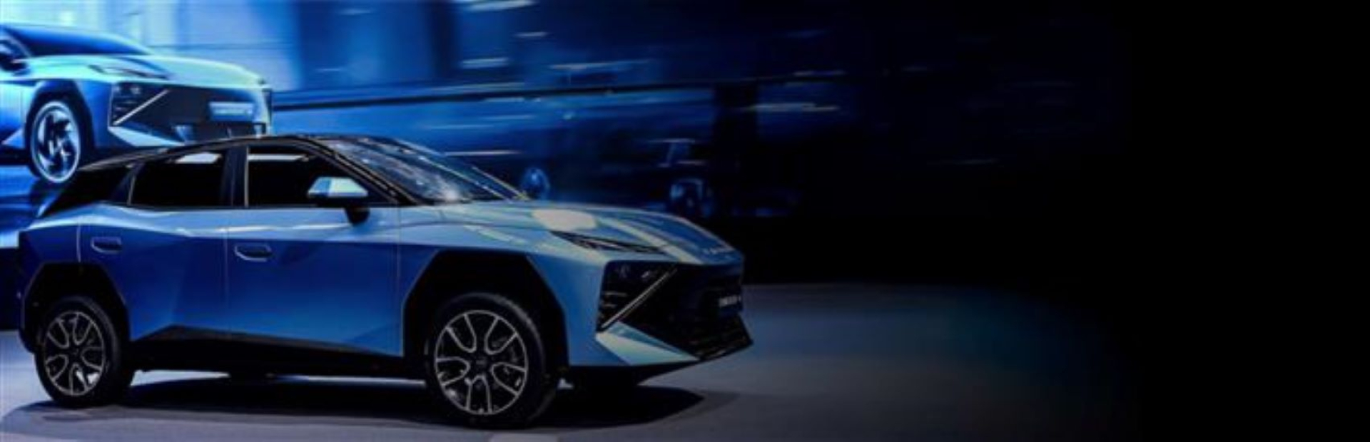 Blue car showcased at an event, viewed from the side.