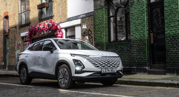 Silver SUV parked on a cobblestone street beside a green-tiled building.
