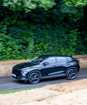 Black SUV driving along a road with straw barriers and trees in the background.