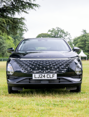 Front view of black Omoda car on grass field.