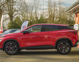 Red SUV parked beside a building in a car dealership.