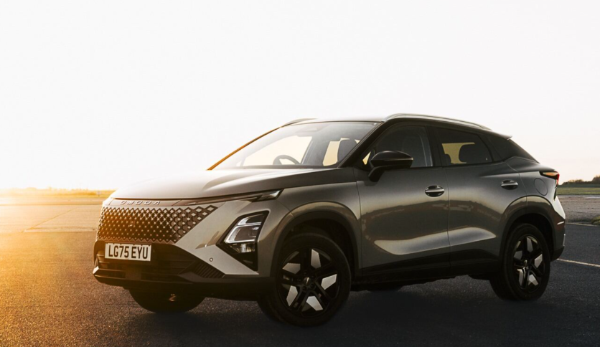 Silver SUV parked on tarmac with headlights and number plate visible.