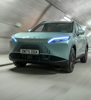 Teal car with distinctive front grille driving in a tunnel.