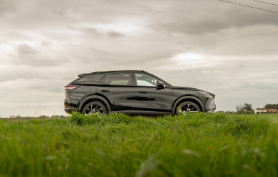 Black SUV parked on grass with cloudy sky above.