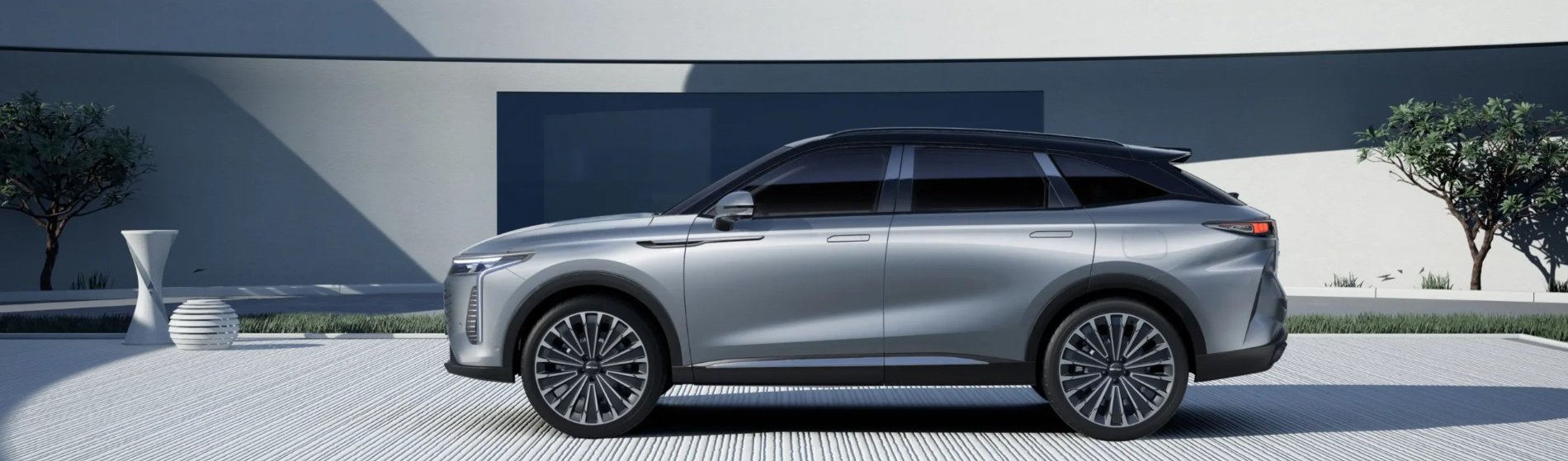 Silver SUV parked with side profile visible, next to a wall with plants.