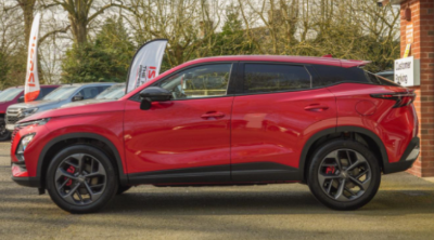 Red SUV parked in front of a building with a visible sign on the side.