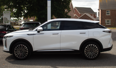 White SUV parked on a street, side profile view.