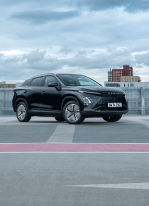 Black car parked on a rooftop with city buildings in the background.