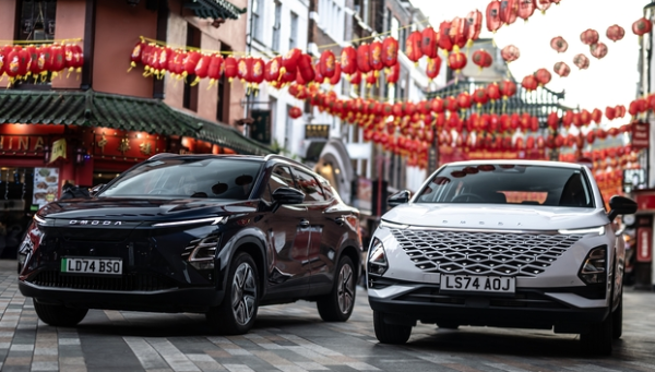 Two Omoda cars parked side by side on a street decorated with red lanterns.
