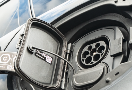 Electric car charging port with open cover and visible connector.