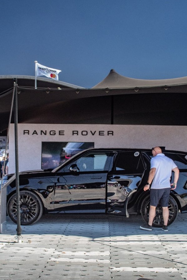 Man looking at a black Range Rover vehicle under a tent.