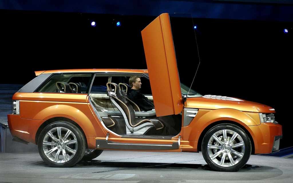Orange concept car with open vertical doors on display.