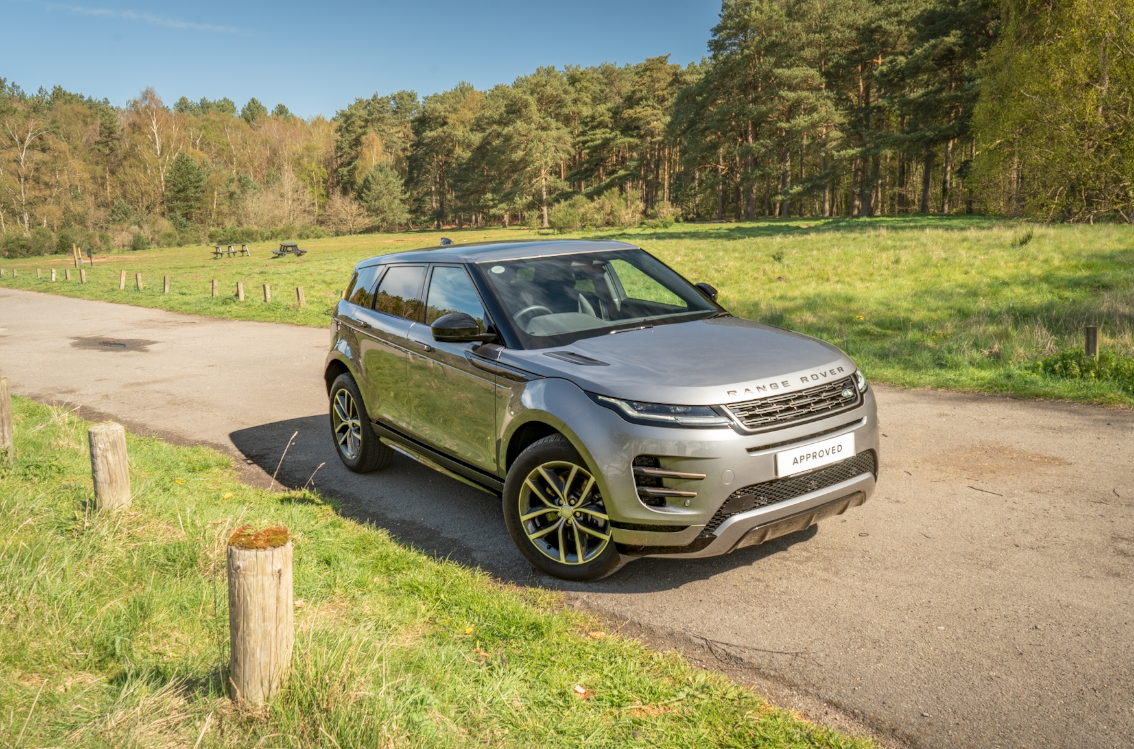 Silver Range Rover Evoque parked on a country lane with trees in the background.