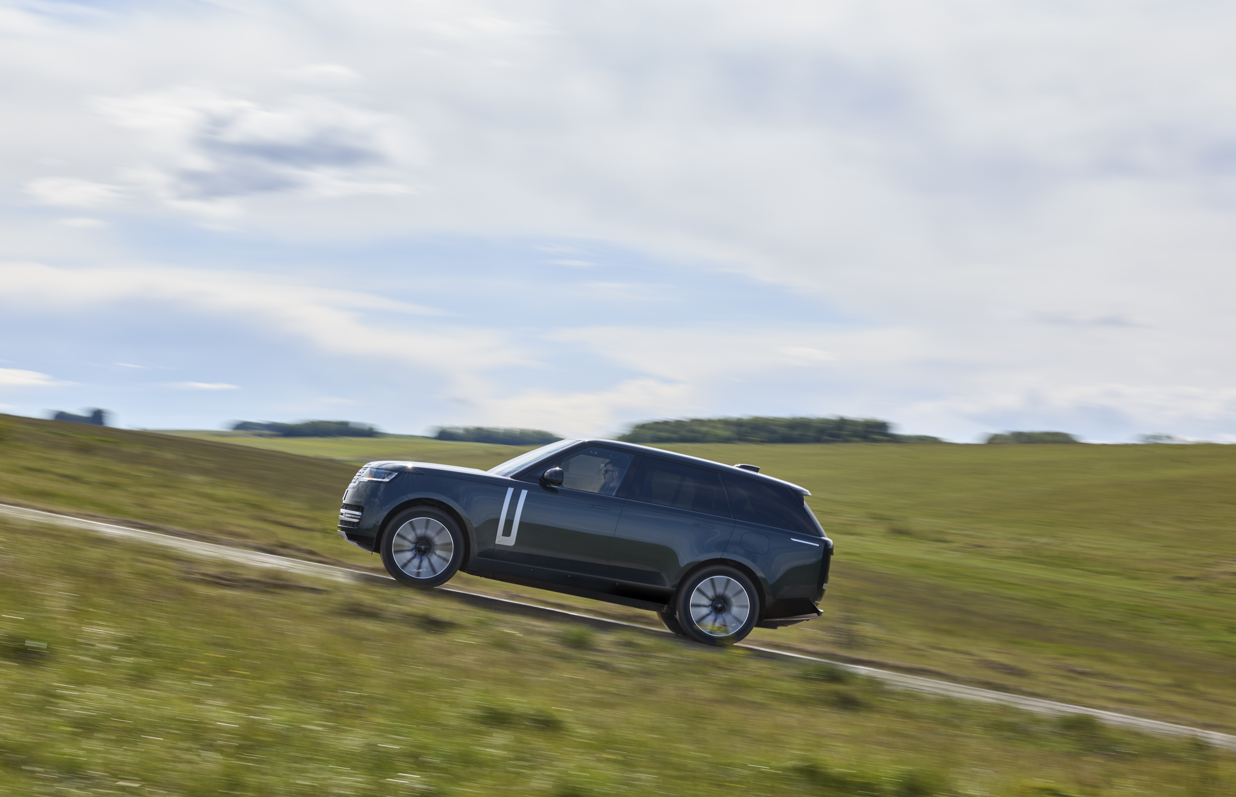 SUV driving uphill on a grassy landscape.