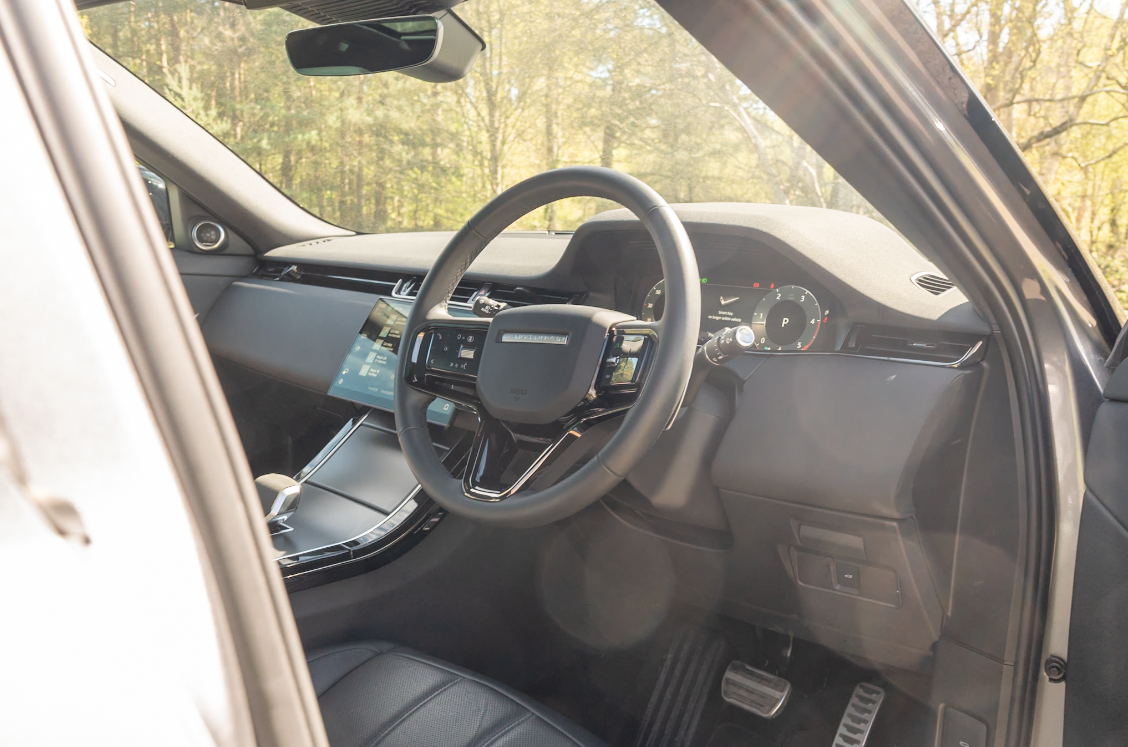 Steering wheel and dashboard of a modern car seen through the driver's side door.