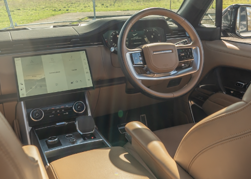Luxury car interior with a tan leather steering wheel and a digital touchscreen display.