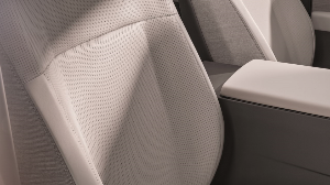 Close-up of light-coloured car seat with perforated texture and grey tones.