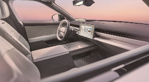 Interior of a car with a steering wheel and two digital displays on the dashboard.