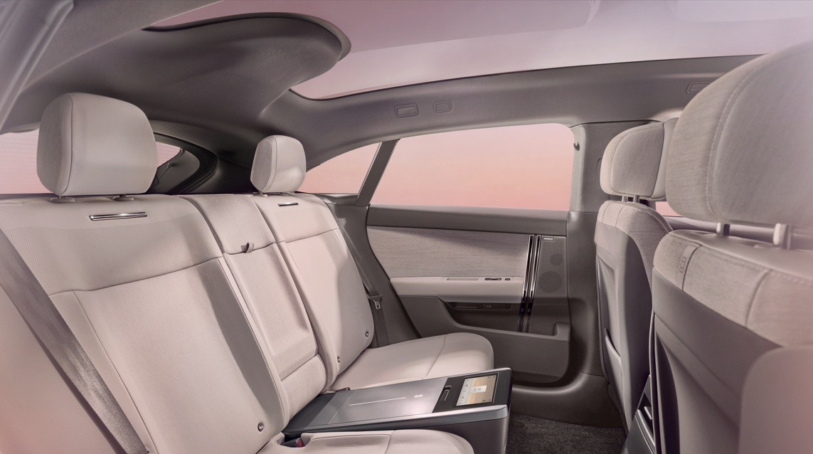 Interior of a car showing beige rear seats and control panel on the armrest.