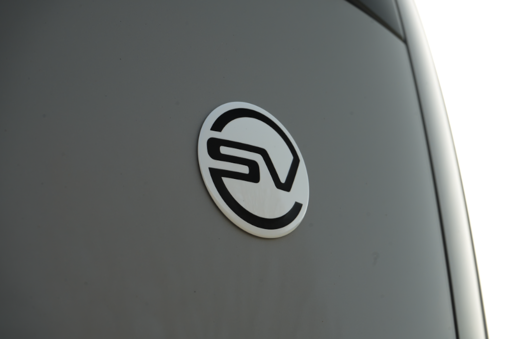 Logo with stylised SV in black on a grey vehicle surface.