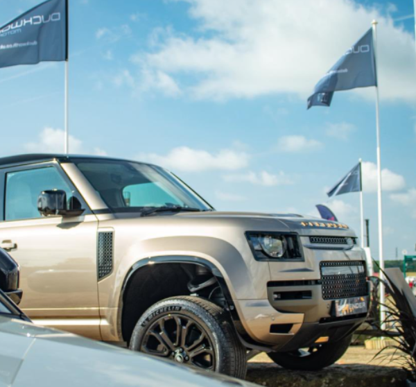 Silver SUV displayed outdoors with three flags in the background.