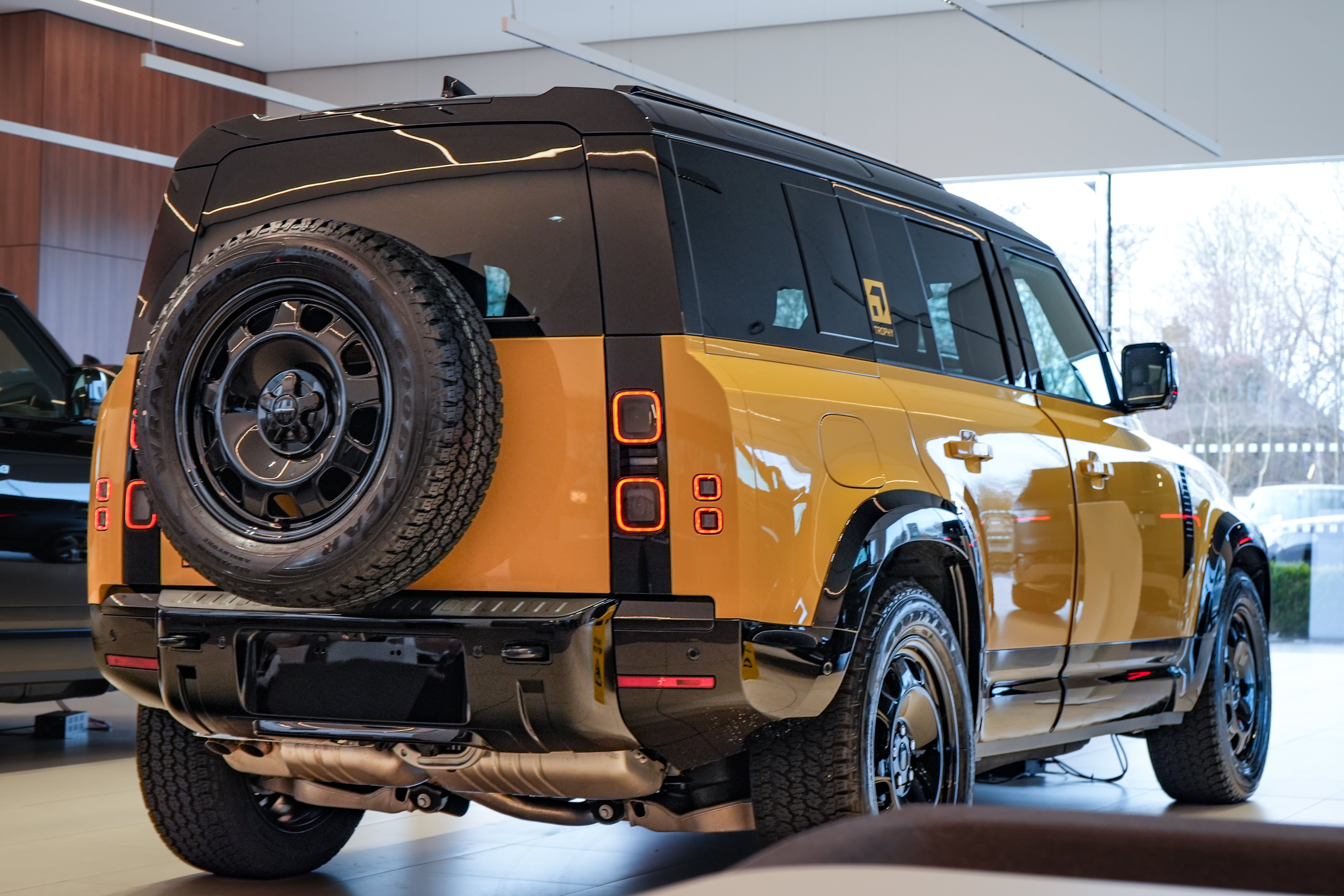 Yellow and black SUV with spare tyre on back, displayed indoors.