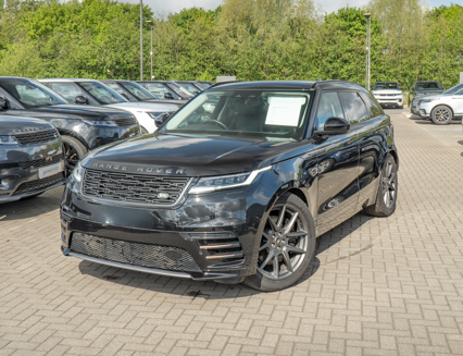 Black Range Rover Velar parked on paved ground with other cars visible nearby.